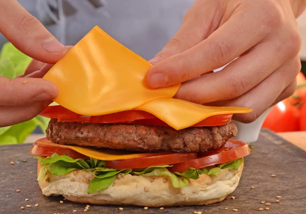 Hands holding and preparing hamburger. — Stock Photo, Image