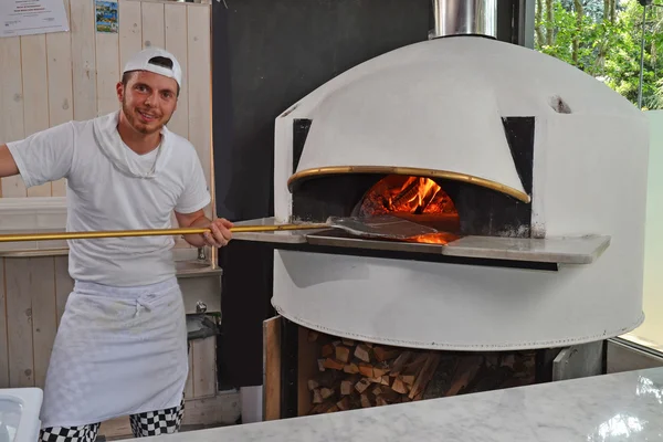 Cuoco tirando fuori la pizza al forno — Foto Stock