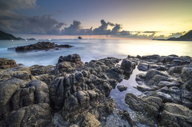 Belanak Beach güçlü su dalgası ve gündoğumu arka plan ile doğal kaya, Lombok, Endonezya