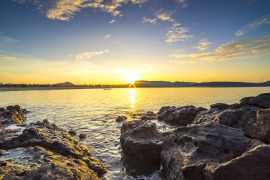 Gündoğumu arka plan ile Plaj kayalar ve su dalgası 