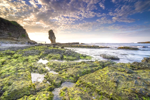 Rock green moss with sunrise background at Pantai Batu Payung ( Umbrella Rock Beach) lombok, Indonesia.