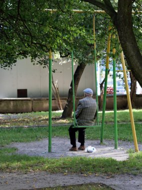Anaokulu yılında bir bankta oturan ihtiyar