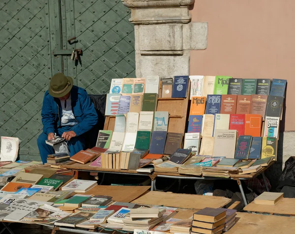 Stock image LVIV, UKRAINE - OCTOBER 4, 2014: Book flea market near the monument of Ivan Fyodorov. Old man looking through second hand book near other books on 4 October 2014, Lviv, Ukraine.