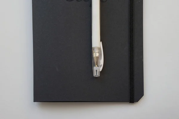 Notitieboekje met zwart papier en witte pen — Stockfoto