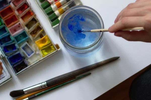 Dibujo con pintura de acuarela y puting abajo cepillo en el agua — Foto de Stock