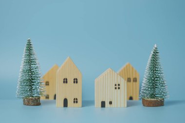 Bir Noel ve Yeni Yıl konsepti, model bir çam ağacı ve mavi arka planda küçük bir ahşap evden oluşur..