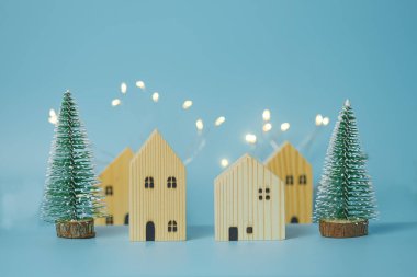 Bir Noel ve Yeni Yıl konsepti, model bir çam ağacı ve mavi arka planda küçük bir ahşap evden oluşur..