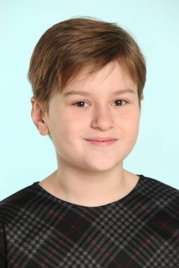 Neşeli ve yaramaz bir genç çocuk yakın plan bir portrede hafifçe gülümser, göz göze gelir..