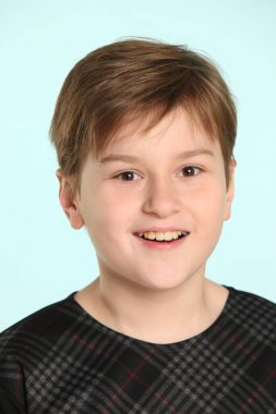 Neşeli ve yaramaz ergen bir çocuk yakın plan bir portrede gülümsüyor..