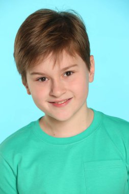 Yakın plan yüz portresi. Yakışıklı, neşeli, genç bir çocuk gözlerinin içine bakar ve büyüleyici bir şekilde gülümser..