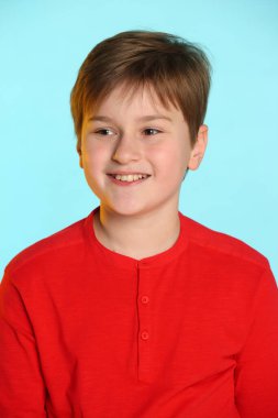 Yakın plan portre: son moda, kırmızı kazaklı neşeli genç çocuk. Gülümsüyor ve çekici bir şeye bakıyor..