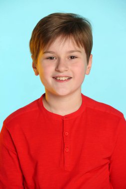 Yakın plan portre: son moda, kırmızı kazaklı neşeli genç çocuk. Gülümsüyor ve göz göze geliyor..