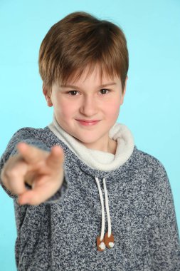 Portrede, yakışıklı, zeki genç bir çocuk neşeyle gülümser, gözlerinin içine bakar ve iki parmağıyla ileri doğru işaret eder..