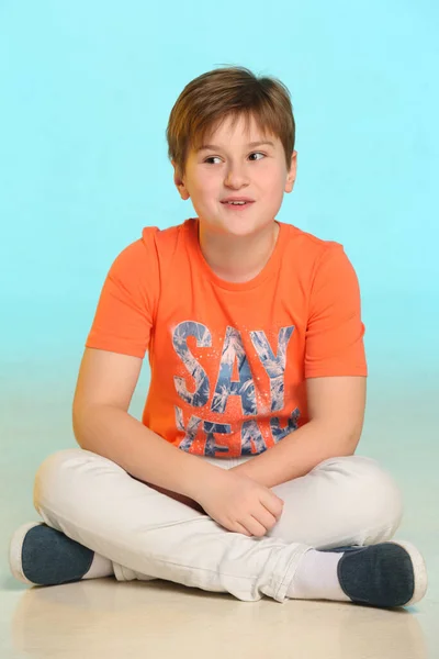 Een Knappe Modieuze Ontwikkelde Vrolijke Tienerjongen Een Oranje Shirt Zit — Stockfoto