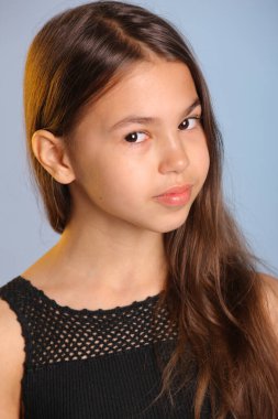 Siyah saçlı, parlak siyah saçlı bir kızın yakın plan portresi. Kahverengi gözleri göz göze geliyor..