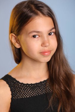 Siyah saçlı, parlak siyah saçlı bir kızın yakın plan portresi. Kahverengi gözleri göz göze geliyor..