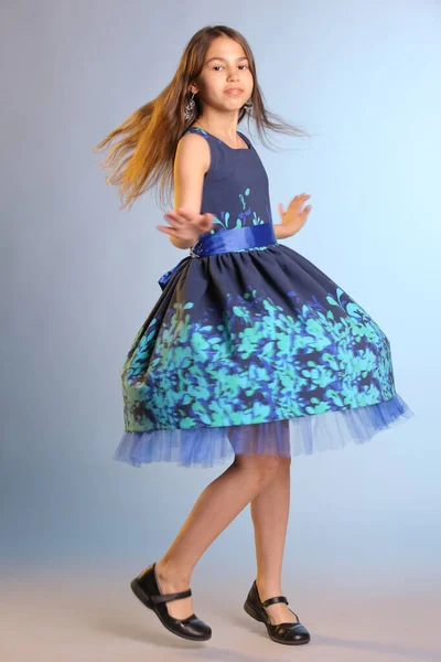 12岁穿着蓝色连衣裙的漂亮瘦小的黑发少女在跳舞旋转 — 图库照片