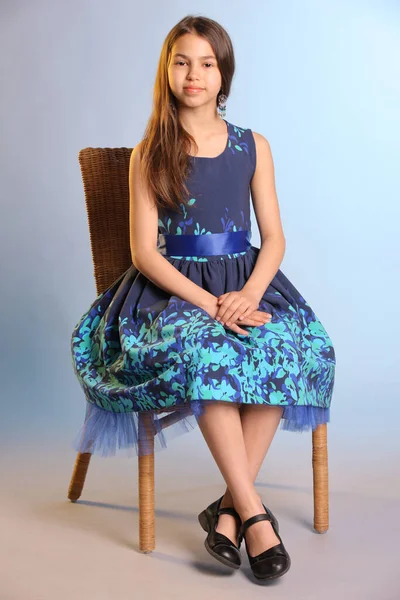 12岁的小女孩 身穿蓝色连衣裙 张开双臂 坐在椅子上 这幅全长的画像描绘了一个可爱的黑发少女 — 图库照片