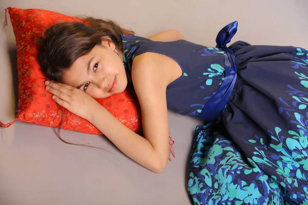 一个可爱的黑头发少女的肖像12岁 她躺在红色的枕头上笑着 — 图库照片