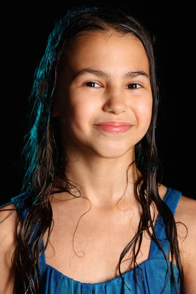 黒の背景に濡れた髪の明るいかわいい陽気なブルネットの女の子のクローズアップ肖像画 青いドレスを着た12歳の少女が雨の中で捕らえられた — ストック写真