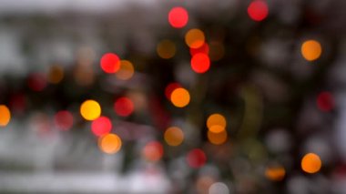 Yılbaşı ağacının bulanık silueti ve odağında parlayan ışıklar. Dikey 4k video. İç kısımda noel ağacı ve sönmüş ışıklar. Noel 'in bulanık geçmişi. Xmas ağacından ışık bokeh. 