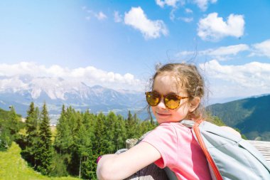 Çocuklar güzel bir yaz günü Alp dağlarında yürüyüş yapıyor Avusturya 'da, kayaların üzerinde dinleniyor ve dağ zirvelerinin muhteşem manzarasına hayran kalıyorlar. Çocuklarla aktif aile tatili eğlencesi. Açık hava eğlencesi ve sağlıklı aktiviteler..
