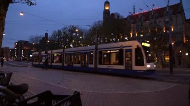 Modern tramvay Leidseplein 'e geliyor. Amsterdam şehir merkezi. İnsanlar aydınlık sokaklarda ve dekore edilmiş binalarda yürümeyi seviyor. Amsterdam mı? 14 Kasım 2020. Amsterdam mı? Hollanda