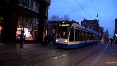 Modern tramvay Leidseplein 'e geliyor. Amsterdam şehir merkezi. İnsanlar aydınlık sokaklarda ve dekore edilmiş binalarda yürümeyi seviyor. Amsterdam mı? 14 Kasım 2020. Amsterdam mı? Hollanda