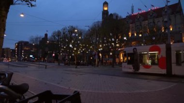 Modern tramvay Leidseplein 'e geliyor. Amsterdam şehir merkezi. İnsanlar aydınlık sokaklarda ve dekore edilmiş binalarda yürümeyi seviyor. Amsterdam mı? 14 Kasım 2020. Amsterdam mı? Hollanda