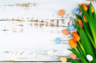 Paskalya bayramı beyaz ahşap masada lalelerle benekli yumurtaları sepete boyamıştı. Geleneksel bahar kompozisyonu ilkbahar için Paskalya elementleri çiçekler ve yumurtalar. Bahar dekorasyonu konsepti.