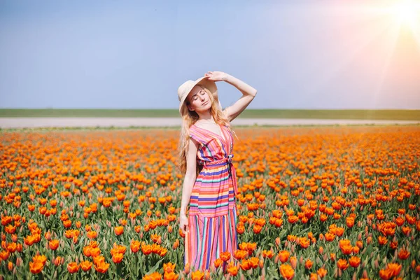 Beautiful red hair woman wearing in striped dress standing on colorful tulip flower fields in Amsterdam region, Holland. Magical Netherlands landscape with tulip field. Trevel and spring concept — Stock Photo, Image