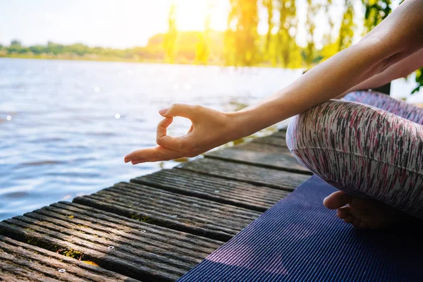 Parkta yoga yapan genç bir kadın. Kız yoga pozisyonunda egzersiz yapıyor. Nilüfer pozisyonunda oturup yoga yapan mutlu ve sağlıklı bir kadın. Gün batımında meditasyon ve spor.