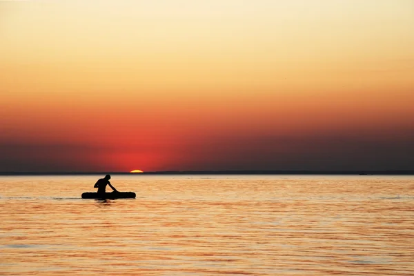 Een man in een boot bij zonsondergang — Stockfoto