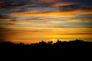 Yumuşak sarı bulutlar gökyüzünde bir gün batımı sırasında bulanık.