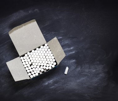 Box with pieces of chalk on a  blackboard clipart