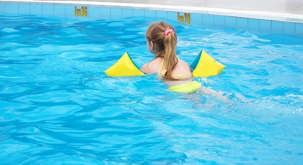 A menina aprende a nadar na piscina exterior — Fotografia de Stock
