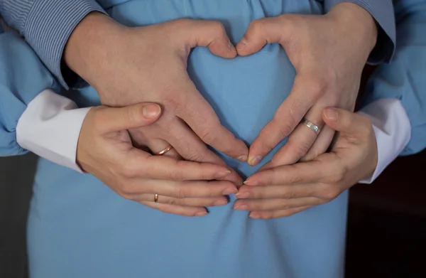 Η έγκυος κοπέλα σε ένα μπλε φόρεμα με καρδιά από τα χέρια — Φωτογραφία Αρχείου