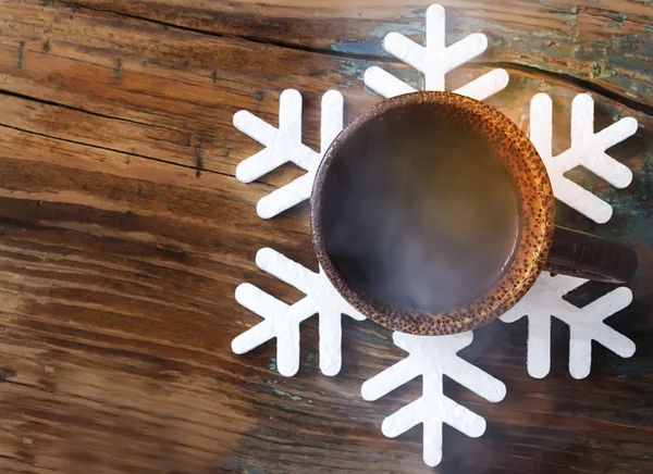 Tasse mit heißem Kaffee auf der Unterlage in Form einer Schneeflocke — Stockfoto