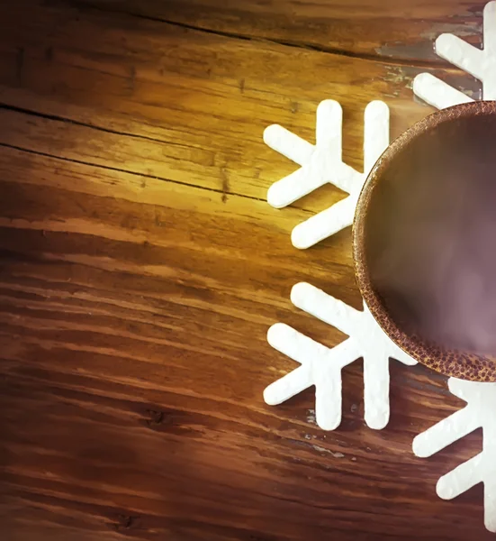 Tasse mit heißem Kaffee auf der Unterlage in Form einer Schneeflocke — Stockfoto