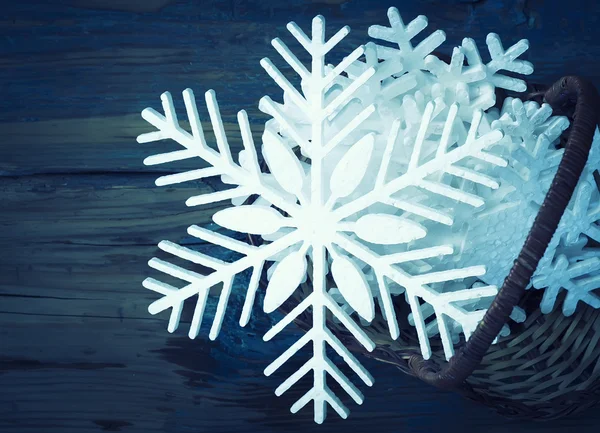 Snowflakes from polyfoam in a basket on wooden texture — Stock Photo, Image