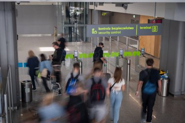 Katowice, Polonya, 7 Mayıs 2024, Katowice Havaalanı 'nın güvenlik kontrol kapıları. Yolcuların geçişi bulanık. Görünür bir güvenlik kontrol levhası, havaalanı içi, editoryal seyahat imgesi.