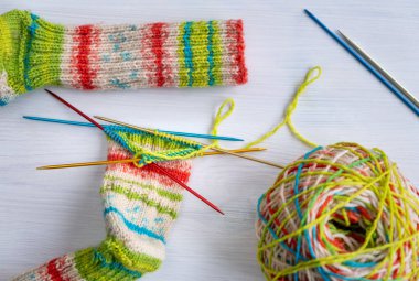 Yün iplik ve iğnelerle sıralanmış örgü projesinin çoraplarının üst görünümü, renkler, doku ve el yapımı zanaat ayrıntıları, örgü, DIY ve hobi temaları için ideal.