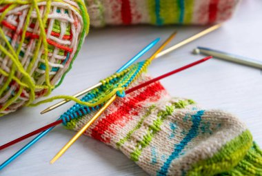 Renkli yün iplikle örülmüş çorap, iğnelerle yakın çekim, hobi için ideal, DIY projeleri ve el yapımı el yapımı temalar.