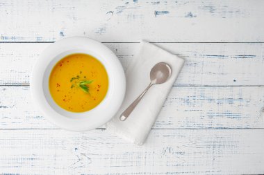 Tahta bir masada beyaz seramik tabakta balkabağı çorbası. Üst görünüm.