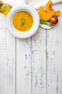 Tahta bir masada beyaz seramik tabakta balkabağı çorbası. Üst görünüm.