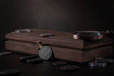Numismatikler. Masanın üzerinde eski gümüş, altın ve bakır paralar var. Özel eldivenli bir koleksiyoncu eski bir para tutar.. 