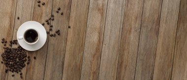 Masanın üzerinde bir fincan kahve ve fasulye var. Üst Manzara. Pankart. Metninizin alanını kopyala