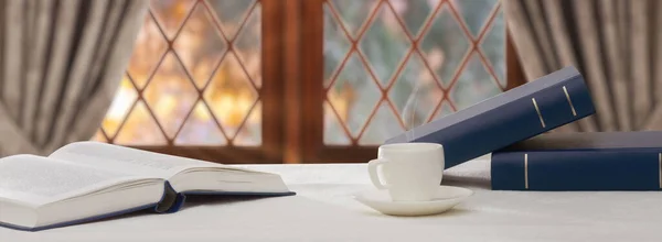 Kitap ve kahve yığını ahşap masada.