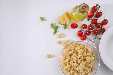 Italian pasta ripe rigate fresh cherry tomatoes, basil, parmesan cheese and olive oil on the table. Top view. Space for tex