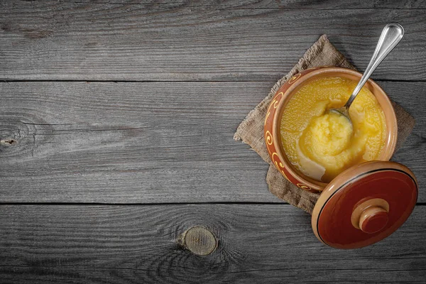 Saf OR Desi Ghee aynı zamanda sıvı tereyağı olarak da bilinir. Saf OR Desi Ghee seramik kaselerde eski ahşap bir masada. Üst görünüm.